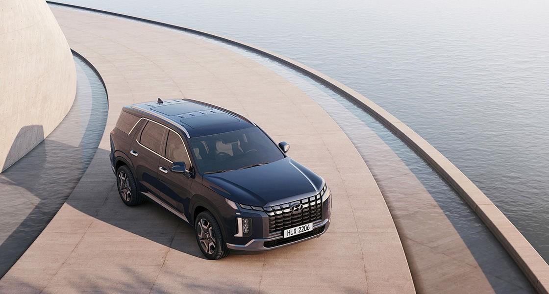 Hyundai Palisade màu xanh đậm nhìn chéo từ trên cao bên mặt nước